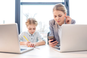 Mother and daughter using online resources for homeschooling at their laptops